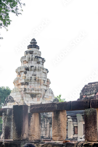 Ancient stone sanctuary pagoda framed by historical sandstone pillars and ruins under bright daylight