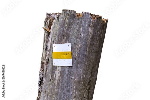 Wooden tree stump with a yellow tourist hiking trail sign isolated on a white background