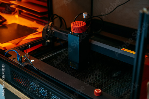 Konstfotografi Diode laser module with red cover stands on honeycomb bed of desktop engraving machine