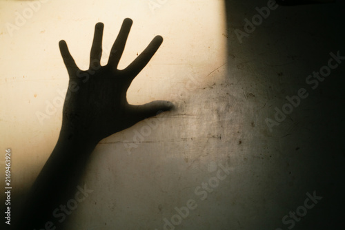 Close up shadow of open palm hand gesture on the white dirty wall