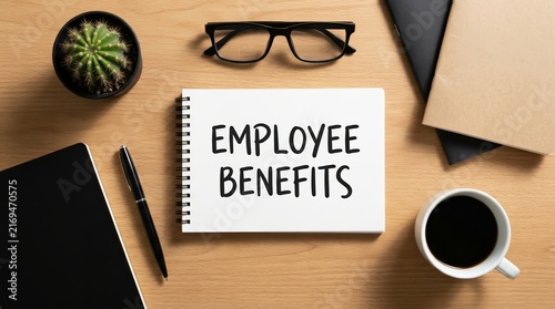 A top view of employee benefits written on a white notebook on a wooden desk.