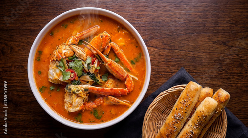 Celebrate crab soup day with this gourmet seafood stew served alongside toasted sourdough bread on a rustic wooden table for a cozy and warm dining experience
