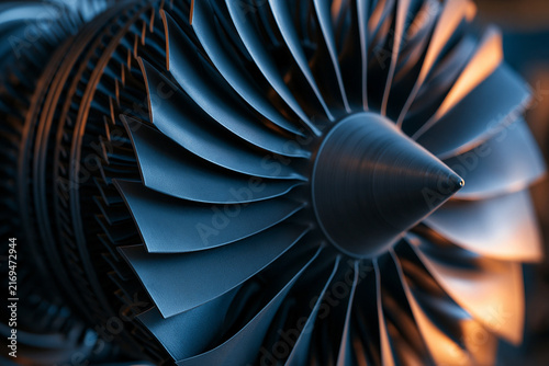 A detailed close-up of a sleek turbine engine fan with intricate metallic blades. This represents modern aerospace technology and clean energy concepts.