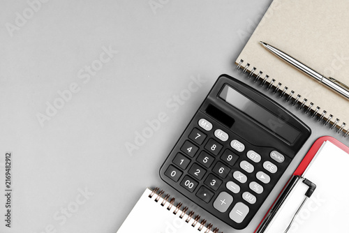 Top view of black calculator with notebooks and pen on gray background with copy space. Concept of accounting, financial planning, budget management, and tax calculation.