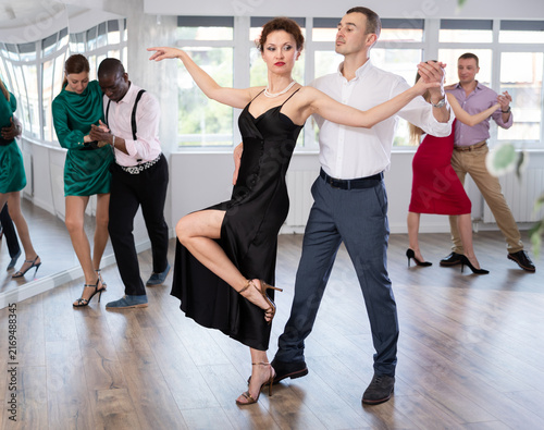 Quadro su tela Graceful woman and young man practicing waltz in pair in dancing studio