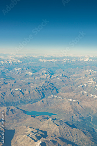 Bright Blue Alpine Lake Nestled Among Endless Rows of Snow-Streaked Mountain Peaks