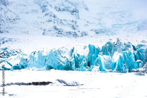 Majestic blue glacier ice against snow-capped mountains in the arctic wilderness of Iceland. High quality photo