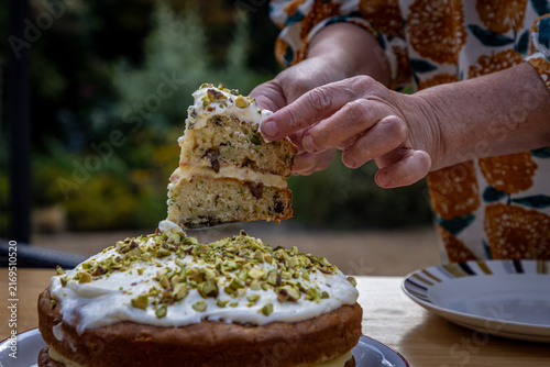 An unrecognisable woman slicing a freshly baked sponge cake, with selective focus