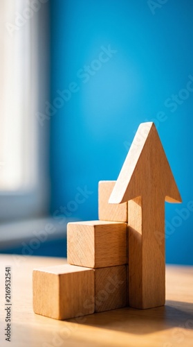 Wooden blocks stacked to form steps with an arrow pointing upwards, symbolizing growth and progress, set against a vibrant blue background.