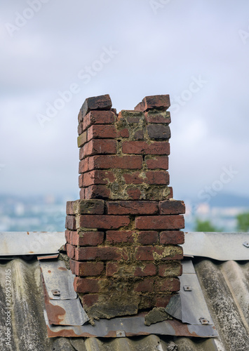 Fotografía Old brick chimney on rusted roof.