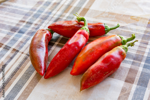 Five ripe red heirloom North Macedonian peppers for ajvar on a rustic tablecloth
