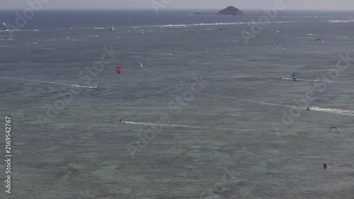 Aerial drone view of kite surfers riding the waves at My Hoa Beach in Vinh Hai, Khanh Hoa, Vietnam, showcasing a spectacular coastal landscape under bright sunlight. 
