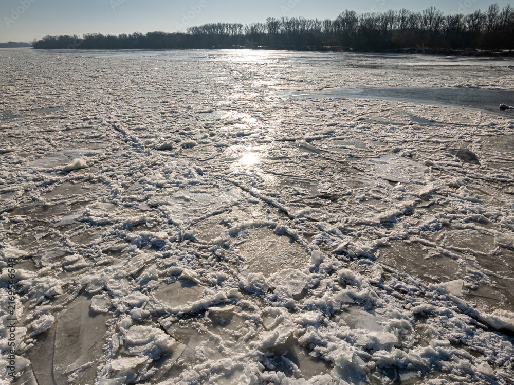 Fototapeta premium Ice floe on frozen Brda River under bridge at sunrise.