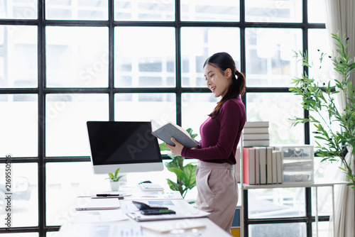 Картината върху платно Asian businesswoman standing working reading documents in modern office