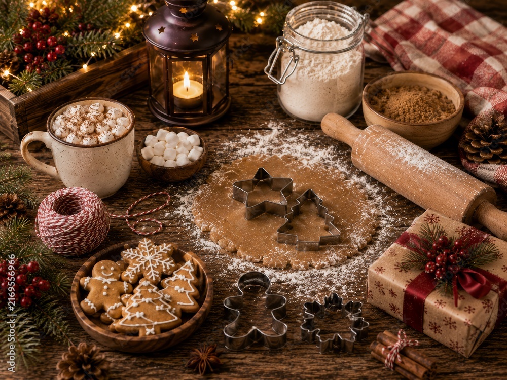 Fototapeta premium Festive holiday baking with gingerbread dough, cookie cutters, and hot cocoa on a rustic table.