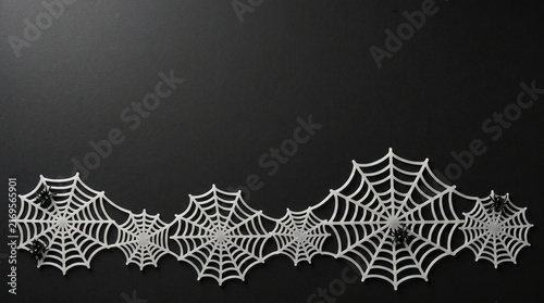 Halloween flat lay with white spider webs on black background for seasonal party decor