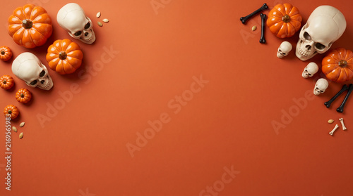 Halloween flat lay background with pumpkins and skulls on orange surface