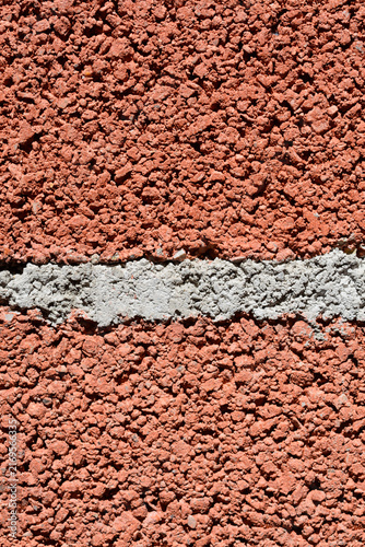 Cuadro en lienzo Detailed view of the rough and grainy surface structure of a red aerated concrete or pumice brick wall with a thick horizontal grey cement mortar line