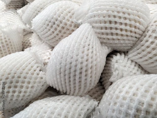Close-up of fresh fruits wrapped in white protective foam mesh netting on display at a retail store, ideal concept for fresh produce packaging, transport, and logistics.
