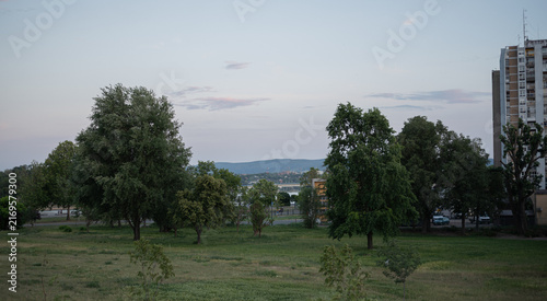 Canvas Print Green grassy park with mature trees sits adjacent to high-rise residential build
