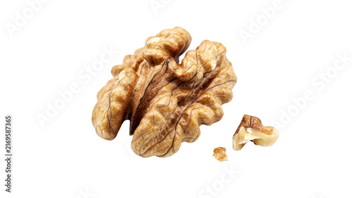 A single raw shelled walnut kernel with small broken pieces isolated on a black background, showing detailed texture and light brown color