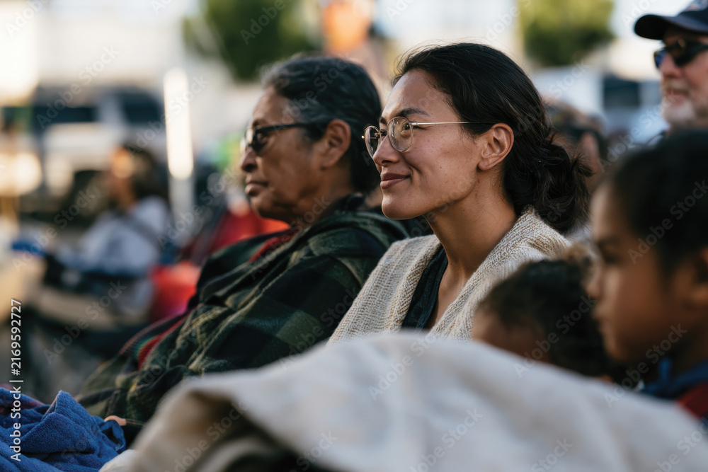 Obraz premium A peaceful scene of friends engaging in conversation outdoors, wrapped in warm blankets, showcasing connections and reflections in a cozy, vibrant environment.
