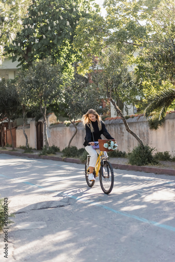Obraz premium Young blonde woman cycling through beautiful streets on a sunny day