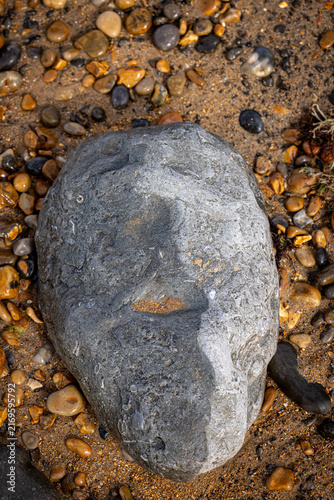 Looking down at a rock appearing to look like a face, on a beach in summer