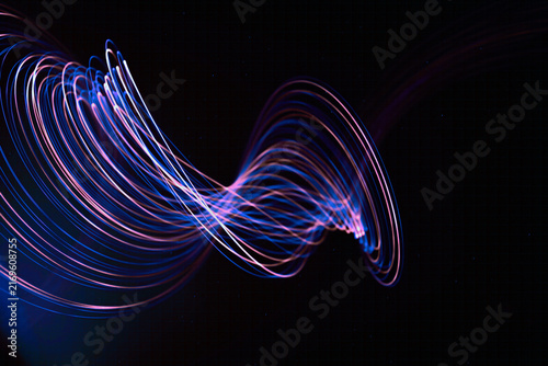 Abstract light trails create dynamic wave patterns on a dark