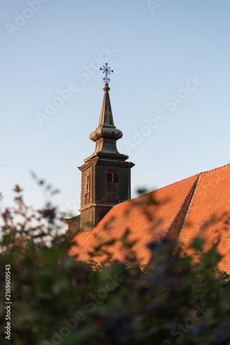 Bild auf Leinwand Historic Petrovaradin church steeple with metal cross rises behind red-tiled roof