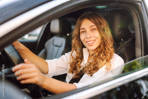 фотографія A happy woman driver is driving a car on a sunny day
