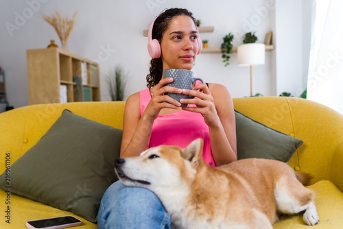 Hispanic Woman relaxes with dog on yellow couch at home in Spain