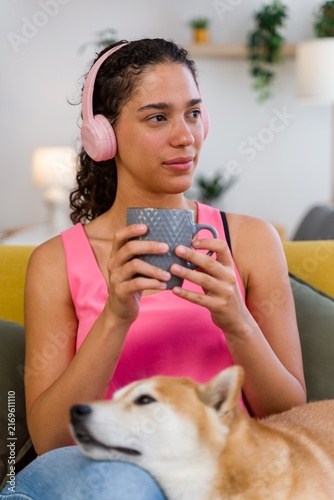 A young Hispanic woman relaxes with her dog and coffee