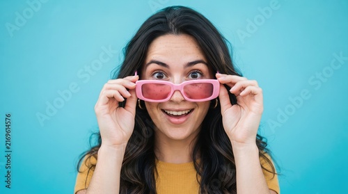 Excited young woman wearing pink 3d glasses looking directly at the viewer with a smile