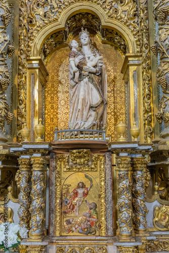An ornate golden altarpiece features a detailed sculpture of the Virgin Mary