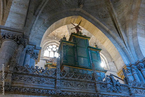 An ornate green organ structure and gothic stone arches