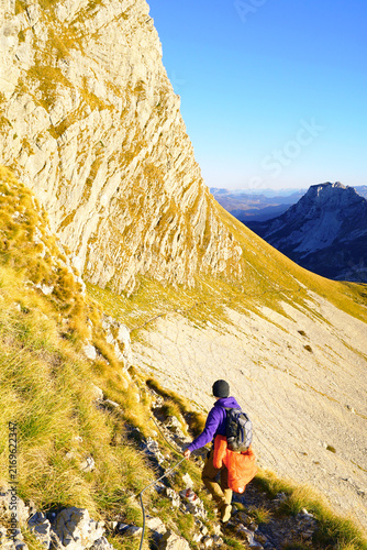 Canvastavla Hiker traverses fixed-rope path along towering limestone wall in Durmitor