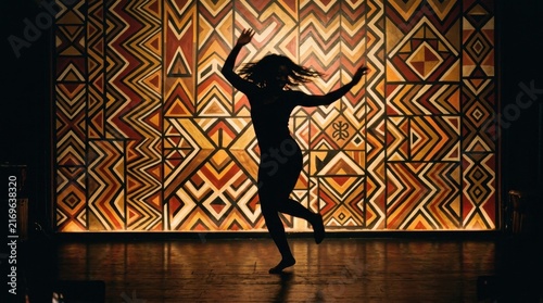 Silhouette of a woman dancing energetically in front of a vibrant geometric African textile pattern
