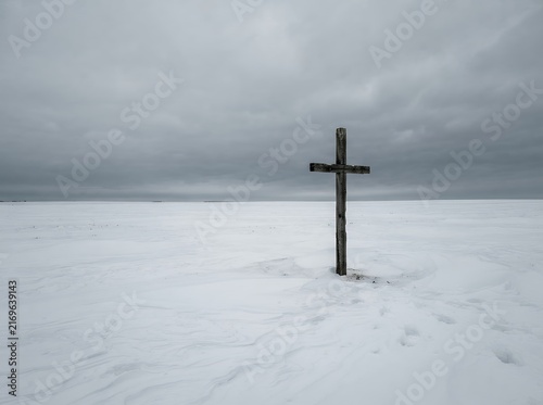 Solitary Cross Standing in a Vast Snowy Landscape Under a Cloudy Sky.