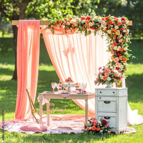 Romantic Outdoor Wedding Arch Decor with Floral Arrangements and Picnic Setup.