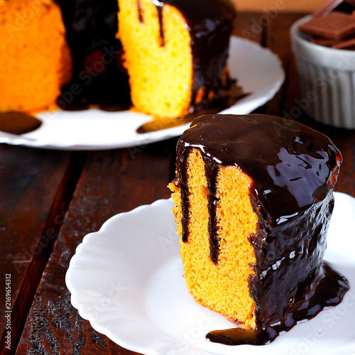 Slice of homemade Brazilian carrot cake with creamy chocolate frosting, served on a white plate.