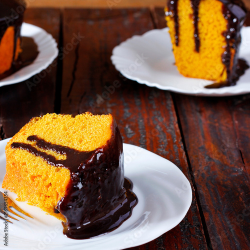 Brazilian carrot cake with chocolate frosting, served on a white plate with slices in the background.