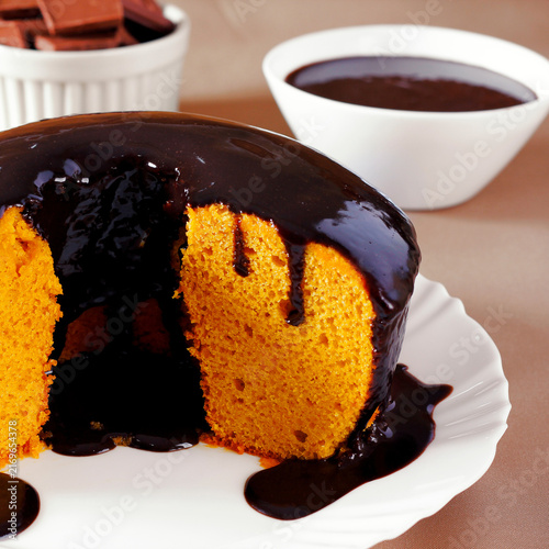 Moist Brazilian carrot cake with a glossy chocolate glaze, served on a white plate.