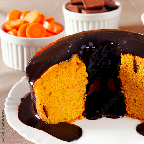 Moist Brazilian carrot cake with a glossy chocolate glaze, served on a white plate.