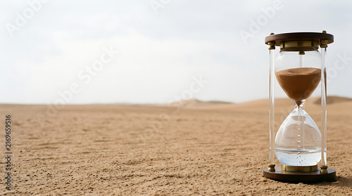 The relentless flow of time, captured in an hourglass resting on the parched sands of a desolate desert landscape
