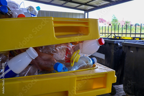 Foto A yellow recycling bin is overflowing with plastic bottles