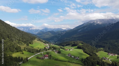 Aerial drone view of the idyllic Bavarian Alps near Ramsau bei Berchtesgaden, Germany, featuring lush green alpine meadows, narrow country roads and majestic mountain scenery. Peaceful rural footage