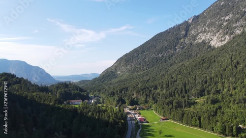 Aerial drone view of a scenic mountain road winding through dense forests and green alpine landscapes near Bischofswiesen, Bavaria, Germany. Drone footage with a calm and relaxing mood.