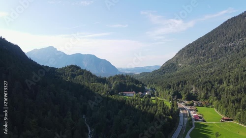 Aerial drone view of a scenic mountain road winding through dense forests and green alpine landscapes near Bischofswiesen, Bavaria, Germany. Majestic Bavarian Alps, lush coniferous forests