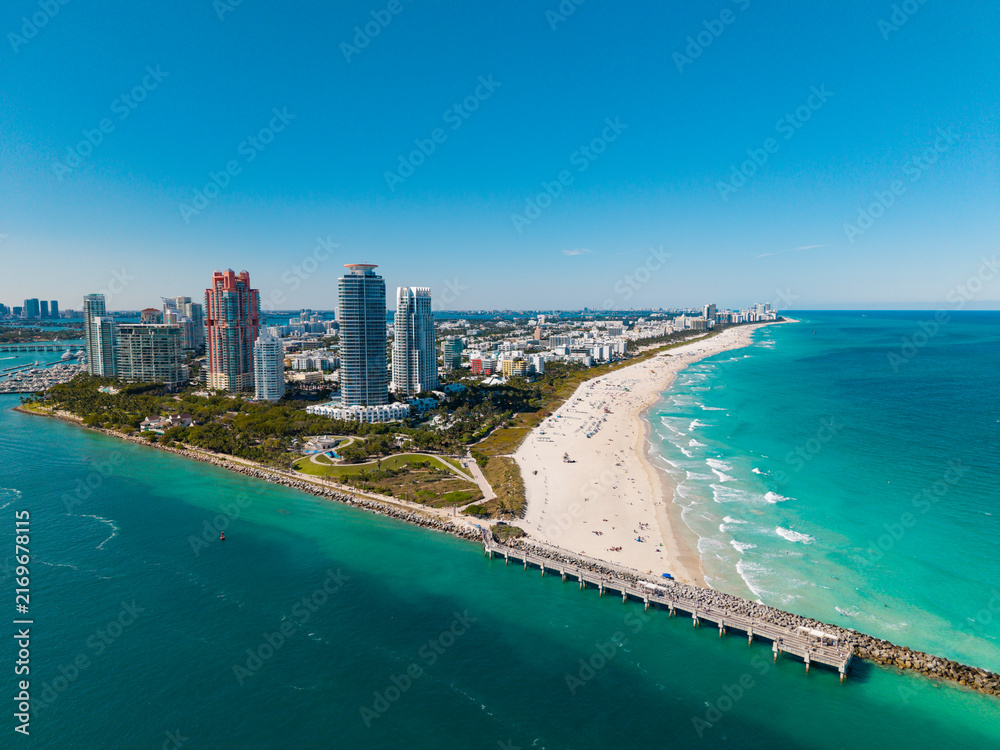 Fototapeta premium Miami Beach on blue sky. Skyline aerial view. Miami city. Tropical Miami scene. Miami district sky view. Famous oceanfront. Panoramic coastline. South beach panorama view. Summer holiday vibes.